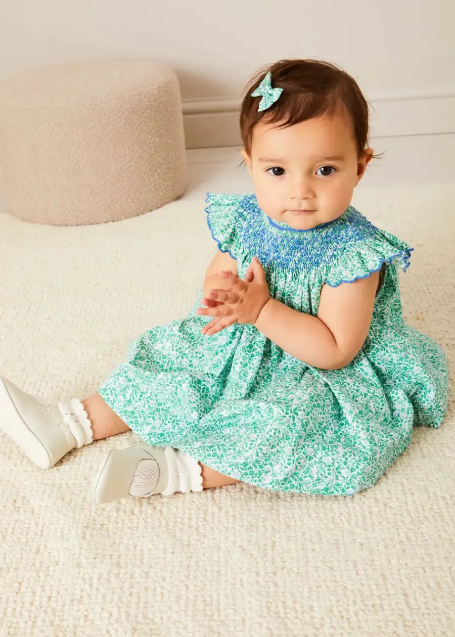 Pepa London Adelaide Floral Hand Smocked Sleeveless Dress With Bloomers in Green (3mths-3yrs) | Openwork Cotton Cardigan in Cream (6mths-10yrs) | Leather Mary Jane Pram Shoes in Ivory (17-20EU) | Adelaide Floral Small Bow Hair Clip in Green | Openwork short socks White (0mths-8yrs) | Flower Fairies of the Spring Book in White