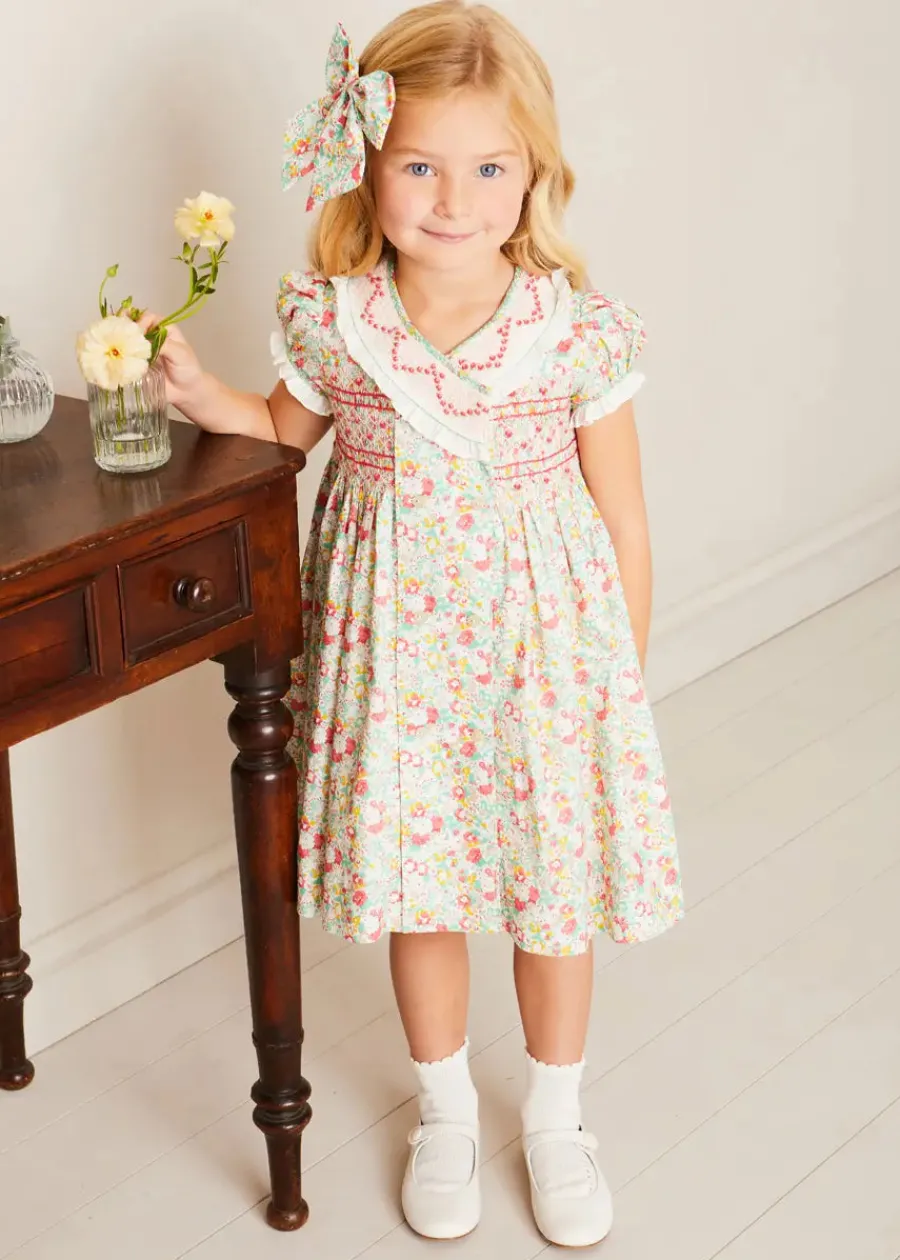 Pepa London Clementine Floral Hand Smocked Double Breasted Short Sleeve Dress in Coral (12mths-10yrs) | Mary Jane Leather Baby Shoes in Ivory (20-24EU) | Clementine Floral Long Bow Hair Clip in Coral | Openwork short socks White (0mths-8yrs)