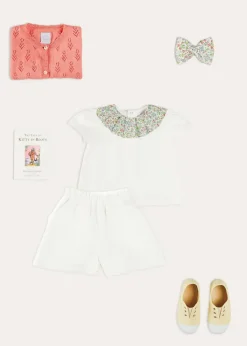 Pepa London Cordelia Floral Collar Top in Pink Made with Liberty Fabric (2-10yrs) | Scallop Trim Embroidered Shorts in White (2-10yrs) | Floral Openwork Cotton Cardigan in Pink (2-10yrs) | Canvas Plimsolls in Cream (20-35EU) | Cordelia Floral Medium Bow Clip in Pink Made with Liberty Fabric | The Tale Of Kitty In Boots Book in White