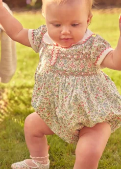 Pepa London Cordelia Floral Hand-Smocked Short Sleeve Romper in Pink Made with Liberty Fabric (3m-2yrs) | Openwork Cotton Knitted Bonnet in Pink (S-L) | Openwork Cotton Cardigan in Pink (6mths-10yrs) | Cordelia Liberty Floral Mary Jane Pram Shoes in Pink (17-20EU) | Flower Fairies of the Spring Book in White | Cordelia Floral Small Bow Clip in Pink Made with Liberty Fabric | Openwork short socks White (0mths-8yrs)