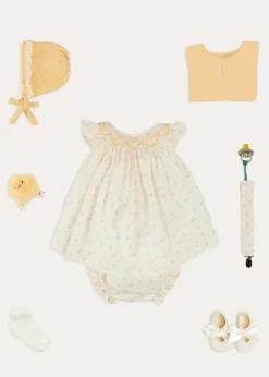 Pepa London Esme Floral Hand Smocked Sleeveless Dress With Bloomers in White (1-12mths) | Openwork Detail Cotton Baby Cardigan in Tangerine (1-12mths) | Lace Detail Knitted Bonnet in Tangerine (1-12mths) | Celebration Ribbon Detail Mary Jane Pram Shoes in Beige (17-20EU) | Esme Floral Dummy Clip in White | Openwork short socks White (0mths-8yrs) | Chick Toy in Yellow | BIBS Dummy in Sage Green