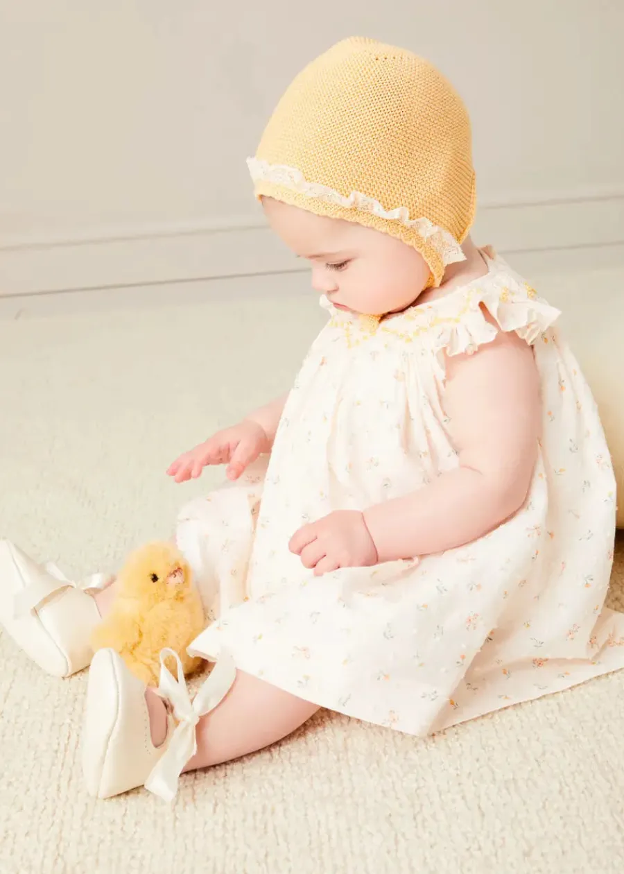 Pepa London Esme Floral Hand Smocked Sleeveless Dress With Bloomers in White (1-12mths) | Openwork Detail Cotton Baby Cardigan in Tangerine (1-12mths) | Lace Detail Knitted Bonnet in Tangerine (1-12mths) | Celebration Ribbon Detail Mary Jane Pram Shoes in Beige (17-20EU) | Esme Floral Dummy Clip in White | Openwork short socks White (0mths-8yrs) | Chick Toy in Yellow | BIBS Dummy in Sage Green