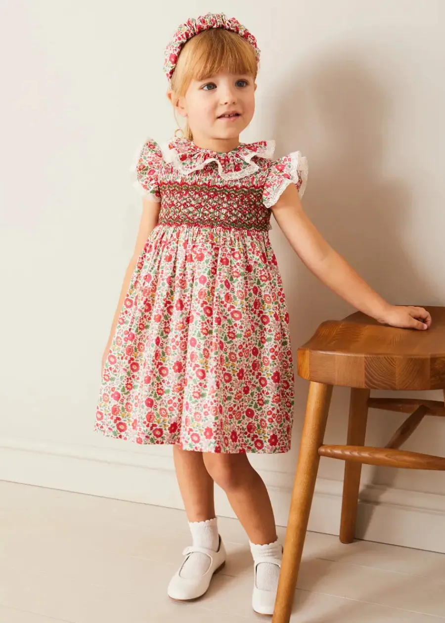 Pepa London Margot Hand-Smocked Dress in Red Made with Liberty Fabric (12m-6yrs) | Openwork Cotton Cardigan in Cream (6mths-10yrs) | Mary Jane Leather Baby Shoes in Ivory (20-24EU) | Margot Liberty Floral Scrunchie Hairband in Red | Openwork short socks White (0mths-8yrs)