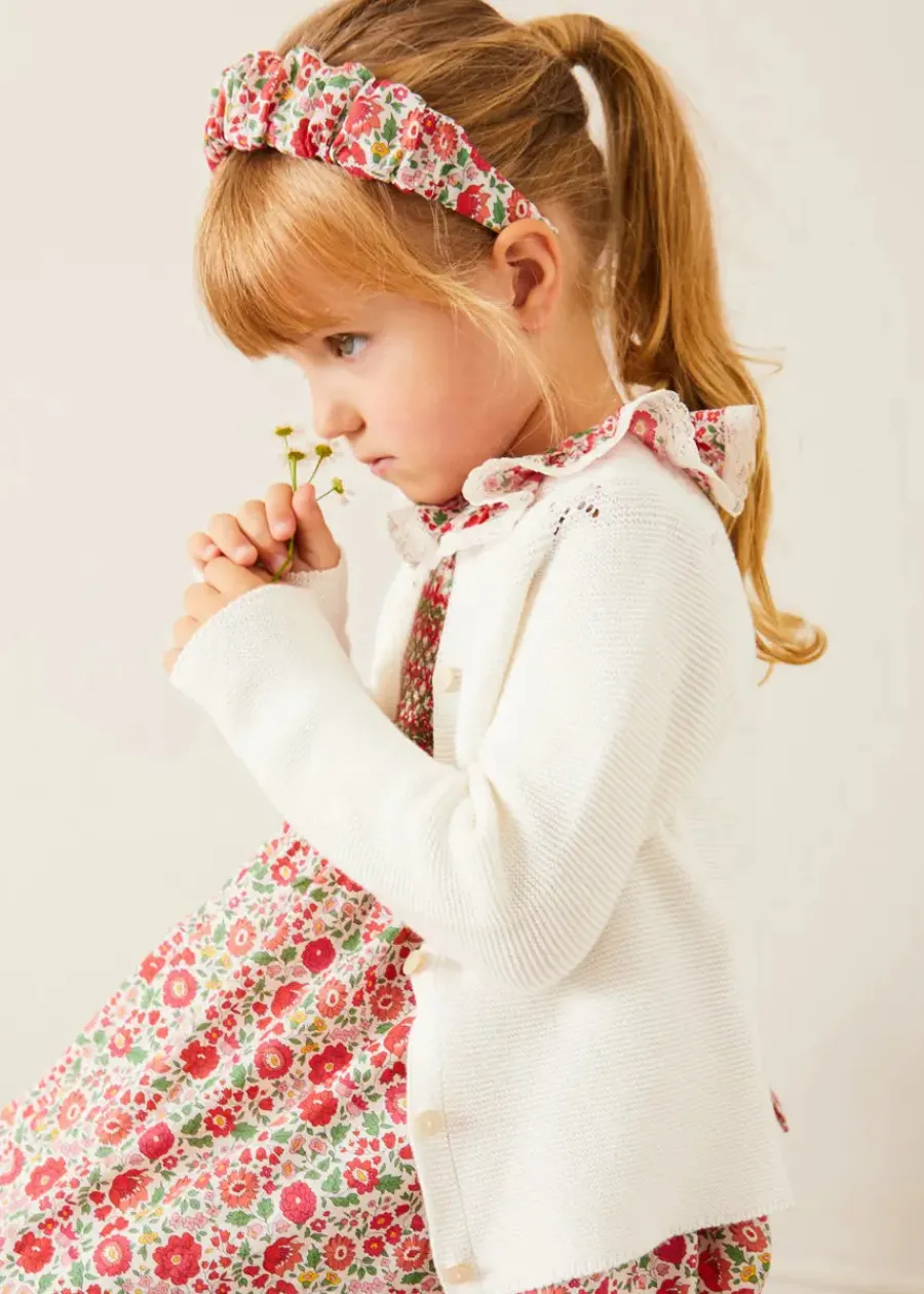 Pepa London Margot Hand-Smocked Dress in Red Made with Liberty Fabric (12m-6yrs) | Openwork Cotton Cardigan in Cream (6mths-10yrs) | Mary Jane Leather Baby Shoes in Ivory (20-24EU) | Margot Liberty Floral Scrunchie Hairband in Red | Openwork short socks White (0mths-8yrs)