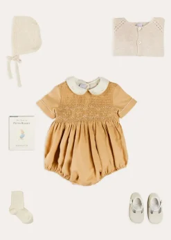 BOY Pepa London Peter Pan Collar Hand Smocked Short Sleeve Romper in Camel (6mths-2yrs) | Plain Cardigan in Cream (6mths-10yrs) | Openwork Knitted Bonnet in Beige(S-L) | T-Bar Leather Pram Shoes in Ivory (17-20EU) | Cotton Short Socks Cream (0mths-10yrs)